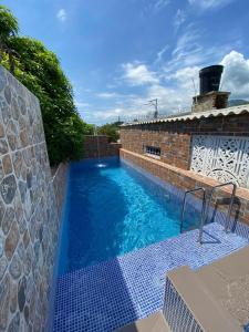 uma piscina num edifício de tijolos com água azul em Cabaña Villa Roma em Santa Marta