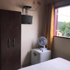 a bedroom with a fan on top of a refrigerator at Aconchego do céu in Conceição da Ibitipoca