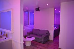 Sala de estar de color púrpura con sofá y mesa en Eaux Spa, en Rouen