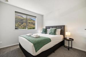 a bedroom with a large bed with a window at Remarkable Mountain View - 4 Bedroom Home in Queenstown