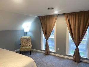 a bedroom with a bed and a chair and windows at Miracle House in Anoka