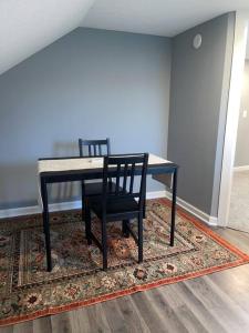 a dining room table with a black chair on a rug at Miracle House in Anoka