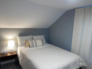 1 dormitorio con cama blanca y mesa con lámpara en Miracle House, en Anoka
