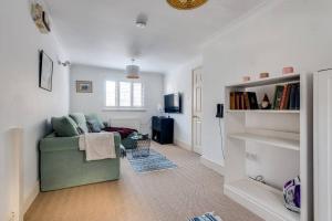 a living room with a green couch and a book shelf at Cosy 2-Bedroom Haven in Picturesque Headington in Oxford