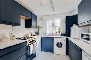 a kitchen with blue cabinets and a washer and dryer at Cosy 2-Bedroom Haven in Picturesque Headington in Oxford