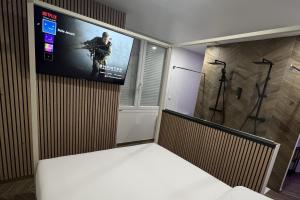 Habitación con TV y videojuego en la pared. en Eaux Spa, en Rouen