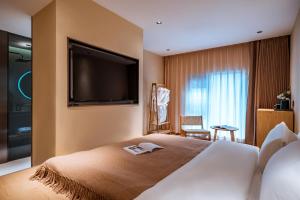 a hotel room with a bed with a flat screen tv at Qingdu - LiYuan Hotel in Dali