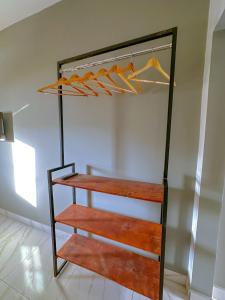 une étagère en bois dans un placard avec des cintres orange dans l'établissement Casa Loft para temporada Guarapari, à Guarapari