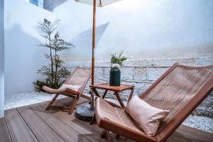 2 sillas y una mesa con sombrilla en el porche en Qingdu - LiYuan Hotel, en Dali