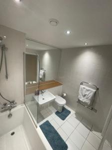 a bathroom with a tub and a toilet and a sink at Manchester Old Trafford CityView En-Suite Apt in Manchester