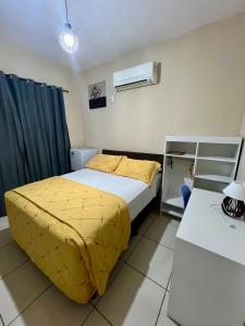 a bedroom with a bed with a yellow comforter at Pousada Riosmar in Balneário Camboriú
