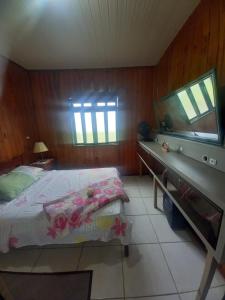 Schlafzimmer mit einem Bett und einer Kommode mit einem TV in der Unterkunft Casa de Veraneio em São Francisco do Sul - Praia do Ervino in São Francisco do Sul