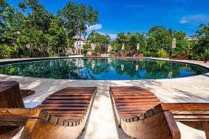 einem Pool mit zwei Holzbänken davor in der Unterkunft Tulum Jungle Villas - Villa Afterlife in Tulum