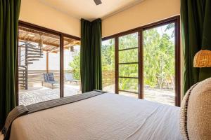 ein Schlafzimmer mit einem Bett und einem großen Fenster in der Unterkunft Tulum Jungle Villas - Villa Afterlife in Tulum