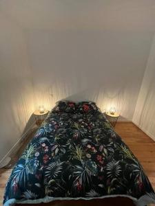 Una cama con una manta de flores encima. en Appartement en cœur de ville, en Mauléon-Licharre
