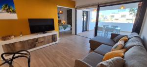 a living room with a couch and a flat screen tv at Casilla de Costa Luz Home con Terrazza Fronte Piscina in La Oliva