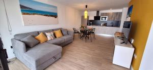a living room with a couch and a kitchen at Casilla de Costa Luz Home con Terrazza Fronte Piscina in La Oliva