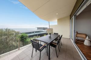a dining room with a table and chairs on a balcony at Groves Sunset Views in Aspendale in Aspendale