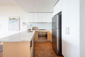 a kitchen with white cabinets and a stainless steel refrigerator at Groves Sunset Views in Aspendale in Aspendale