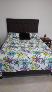 ein Bett mit einer Blumendecke mit einer Katze drauf in der Unterkunft Apartahotel Zamflor in Puerto Asís