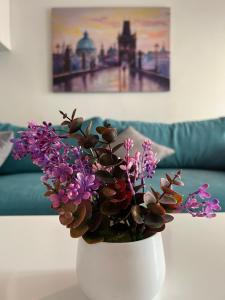 a white vase with purple flowers on a table at Serres city center modern apartment (Monika) in Serres