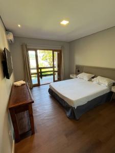 1 dormitorio con cama, mesa y ventana en Pousada Jardim Da Lagoa, en Florianópolis