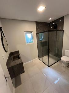 a bathroom with a glass shower and a toilet at Pousada Jardim Da Lagoa in Florianópolis