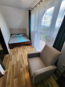 a living room with a couch and a large window at Domki Nad Jeziorem 781-281-434 in Polańczyk