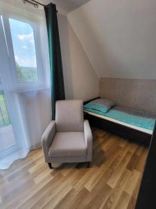 Cette chambre comprend une chaise, un lit et une fenêtre. dans l'établissement Domki Nad Jeziorem, à Polańczyk