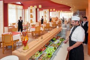 ein Koch steht vor einem Buffet mit Speisen in der Unterkunft Hotel Longosa - All Inclusive in Sonnenstrand