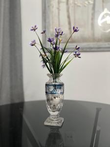 a glass vase with purple flowers in it on a table at Serres city center modern apartment (Monika) in Serres