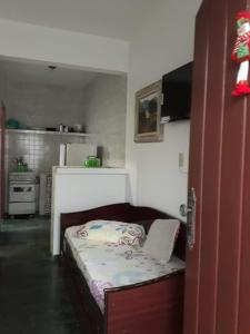 ein kleines Schlafzimmer mit einem Bett und einer Küche in der Unterkunft Chalé na Praia Martim de Sá in Caraguatatuba