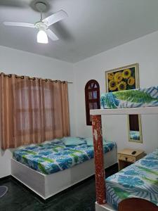 1 Schlafzimmer mit 2 Betten und einem Deckenventilator in der Unterkunft Chalé na Praia Martim de Sá in Caraguatatuba