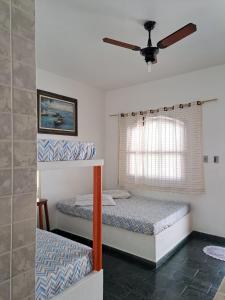 2 Etagenbetten in einem Zimmer mit Deckenventilator in der Unterkunft Chalé na Praia Martim de Sá in Caraguatatuba