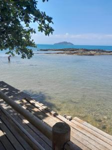 a wooden bench sitting next to a body of water at Sonia Flats - Chalé a 500 metros da Praia da Tartaruga in Búzios