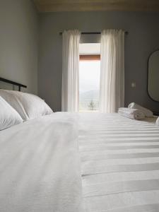 a bedroom with a large white bed with a window at Methydrion Country House in Vytina