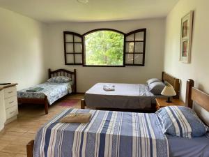 um quarto com 2 camas e uma janela em Recanto da Paz, Miguel Pereira RJ em Miguel Pereira