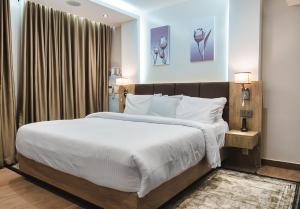 a bedroom with a large bed with white sheets at Sunflower Residence Victoria Island in Lagos