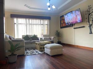 a living room with a couch and a flat screen tv at CASA NUEVA, CON DECORACIONES Y ACABADOS NUEVOS SOLO PARA FAMILIAS. in Cuenca