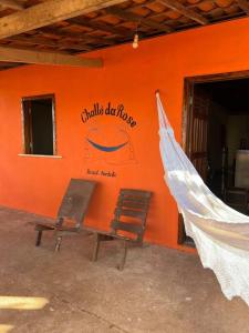 an orange wall with a bench and a sign on it at The Rose's Cottage (Chalé da Rose) in Icapuí