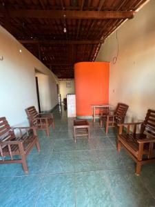 Habitación con sillas y mesas de madera y pared de color naranja. en The Rose's Cottage (Chalé da Rose) en Icapuí
