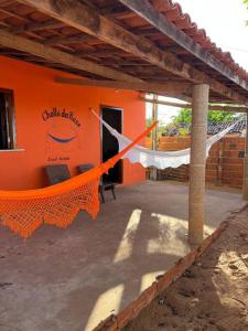 an orange building with a hammock in front of it at The Rose's Cottage (Chalé da Rose) in Icapuí