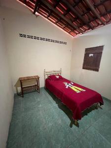 Schlafzimmer mit einem roten Bett und einem Tisch in der Unterkunft The Rose's Cottage (Chalé da Rose) in Icapuí