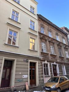 a yellow car parked in front of a building at Centrum Apartamenty Stare Miasto in Kraków
