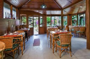 un restaurante con mesas y sillas de madera y ventanas en Aldebaran Pousada, en Visconde De Maua