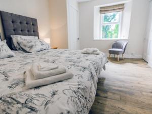 a bedroom with a bed with a blanket and a chair at Keepers Cottage - Uk30246 in Cray