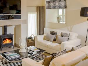 a living room with white furniture and a fireplace at Howgills Barn in Middleton