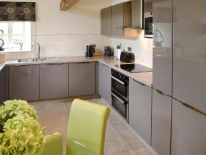 a kitchen with stainless steel appliances and a yellow chair at Howgills Barn in Middleton
