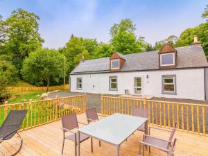 a house with a deck with a table and chairs at Dalnaglar Cottage - Uk30260 in Cray