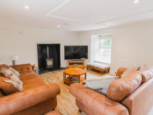 a living room with two brown leather couches and a tv at Dalnaglar Cottage - Uk30260 in Cray
